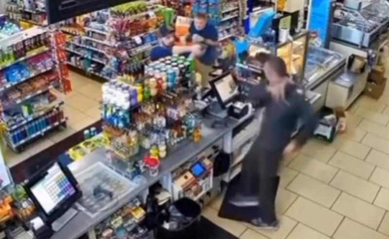 一名藍衣男客正拿著商品要到櫃檯結帳,結果就目擊Pardeep Kumar被槍殺的瞬間。(網上截圖)