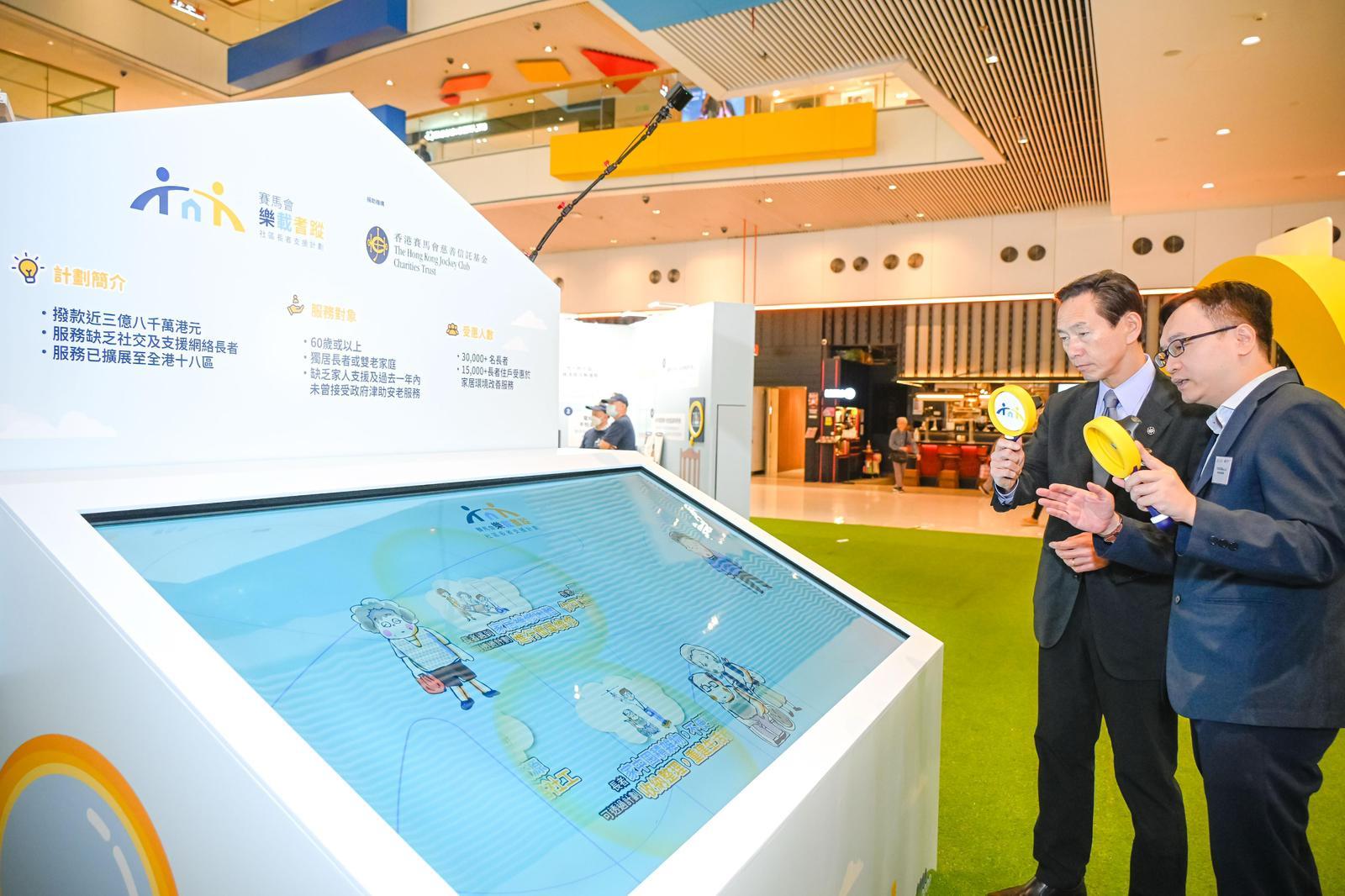 馬會董事陳智思(左)參觀有關「賽馬會樂載耆蹤社區長者支援計劃」的展覽。