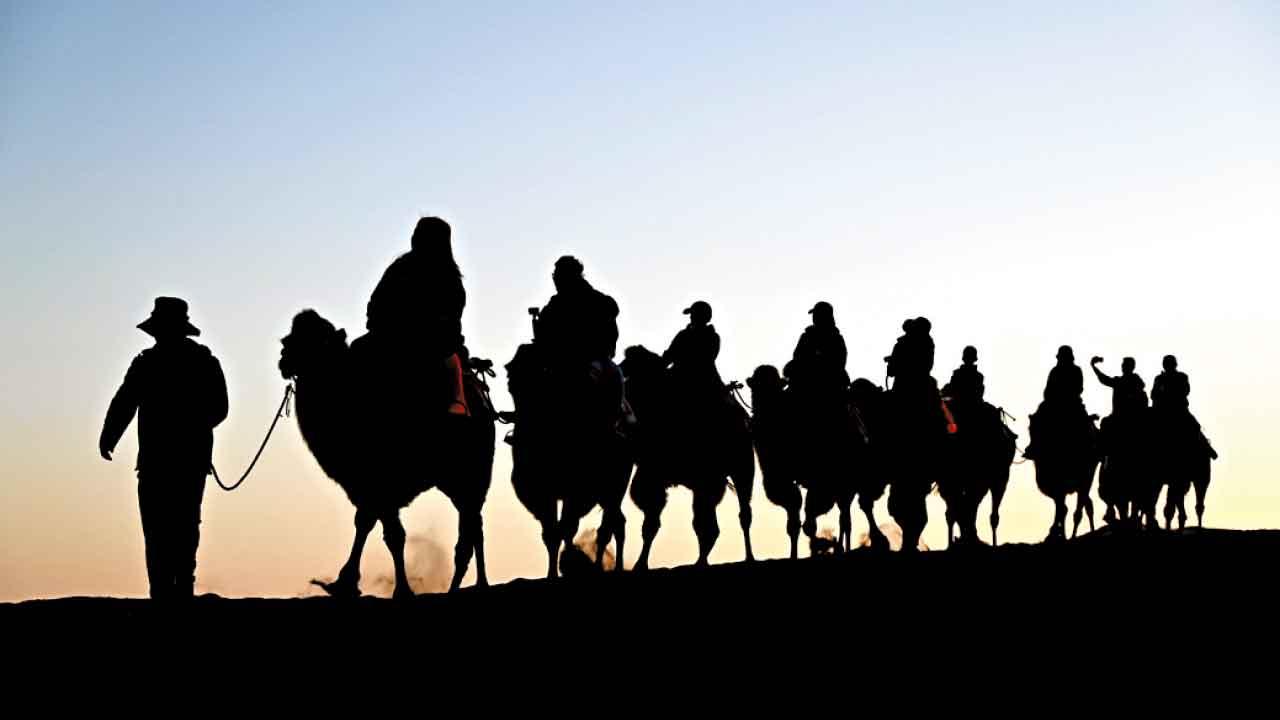 遊客在甘肅省敦煌市鳴沙山月牙泉景區騎駱駝。