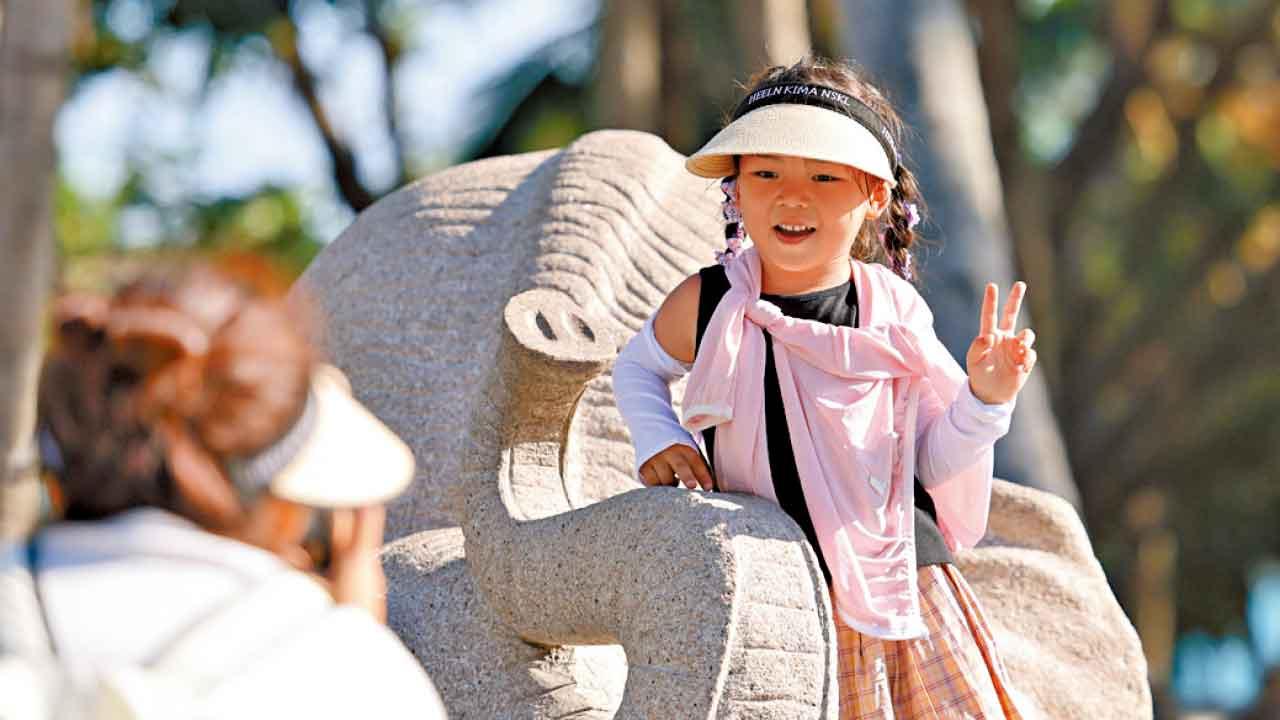 家長帶著孩子在海南三亞南山文化旅遊區遊玩。