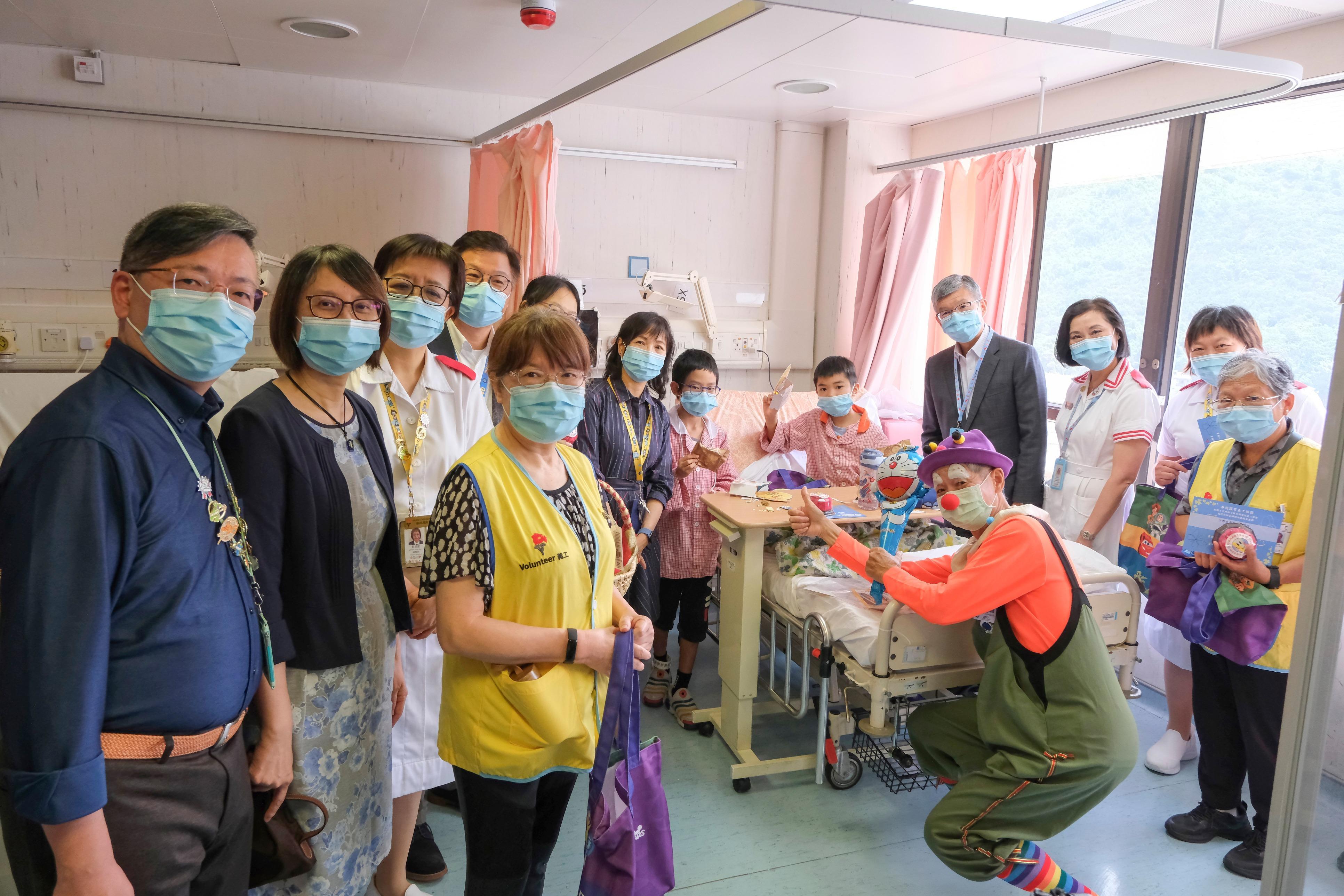 新界東醫院聯網總監鄧耀鏗醫生(後排右四)與義工及同事們一起走訪兒科病房,向病童送上親手製作的豆沙及紫薯月餅、精美禮品包及月餅造型毛巾,讓小朋友感受到中秋的喜悅與關懷。(政府新聞處)