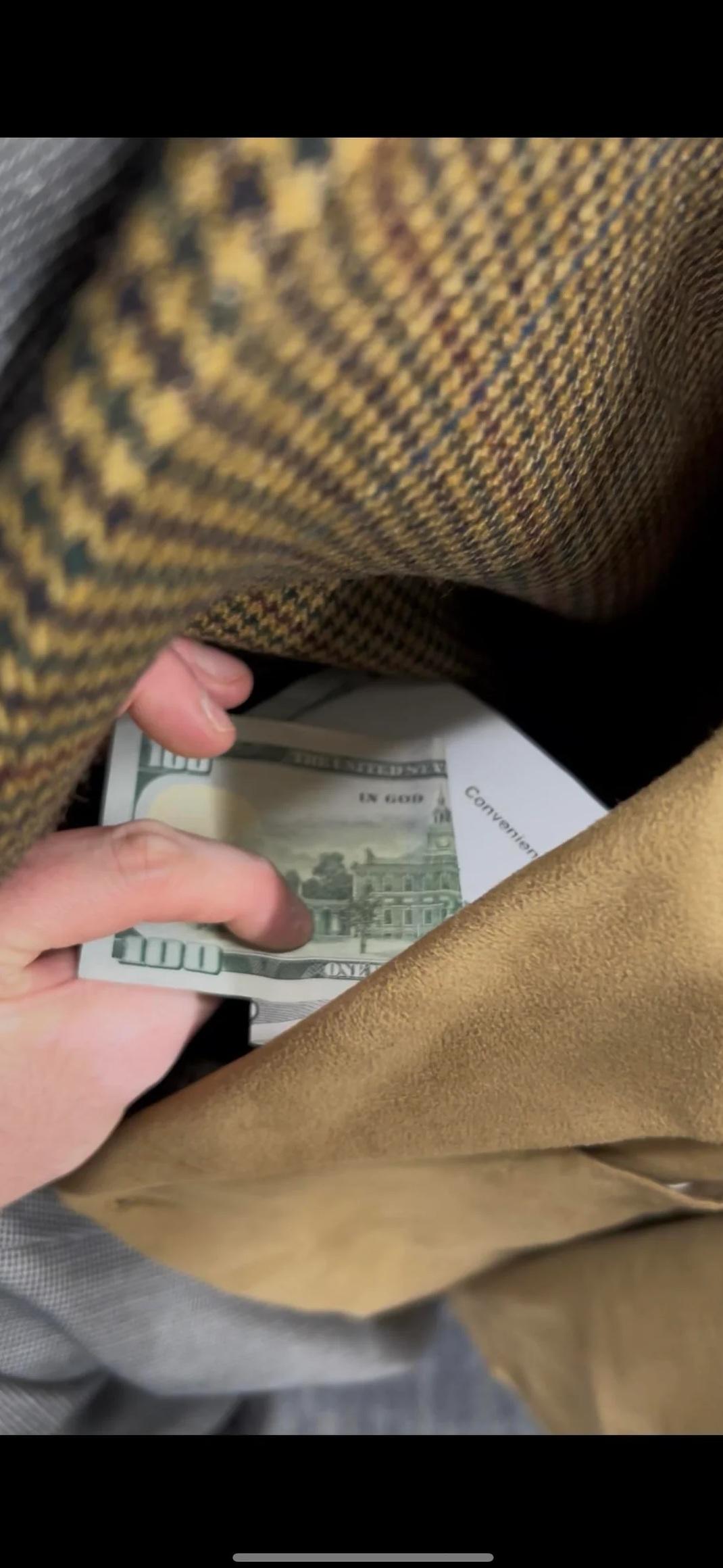 男子拍照,顯示他在二手西裝的衫袋裡發現多張鈔票。(互聯網)