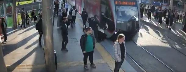 女子沒察覺有電車駛至便過馬路,車站保安員及時伸手拉她回路邊。(互聯網)