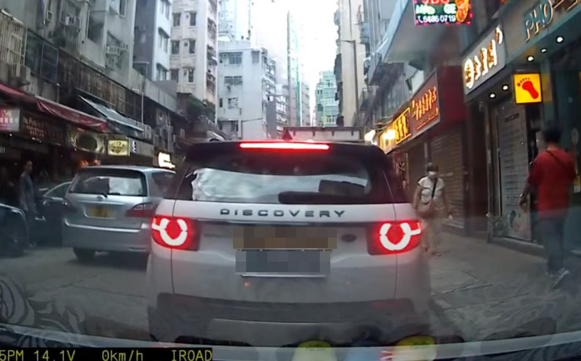 一輛掛住中港兩地牌的白色私家車於佐敦廟街泊車,見有3名成年人及一名男孩下車後,一名黑衫男子打開車尾箱,驚現有3名女童「屈蛇」於儲物位置。(影片截圖)