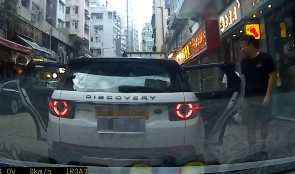 一輛掛住中港兩地牌的白色私家車於佐敦廟街泊車,見有3名成年人及一名男孩下車後,一名黑衫男子打開車尾箱,驚現有3名女童「屈蛇」於儲物位置。(影片截圖)