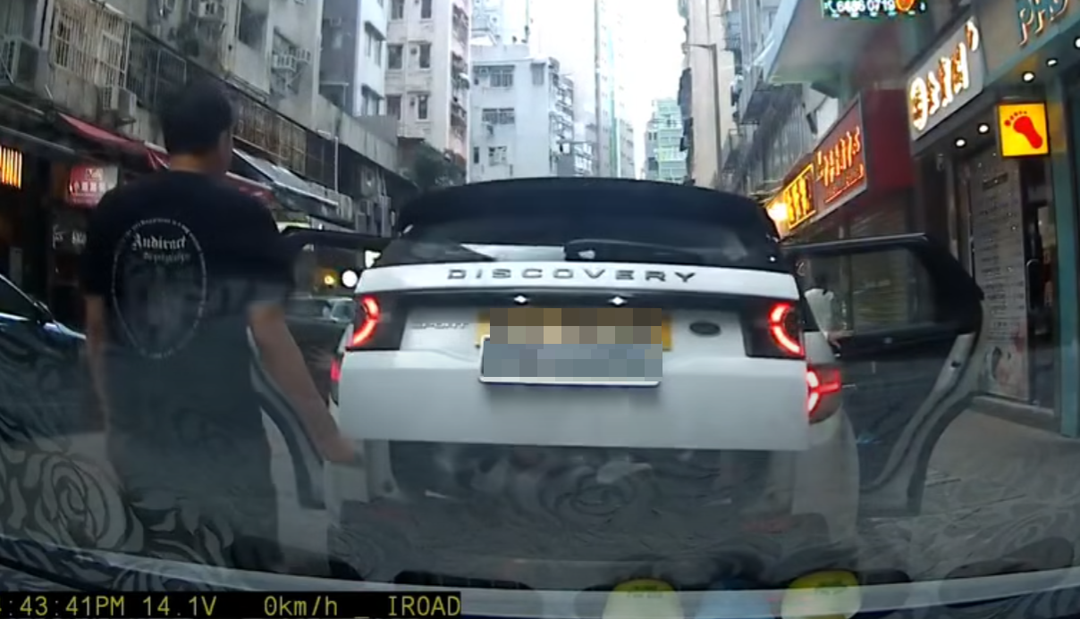 一輛掛住中港兩地牌的白色私家車於佐敦廟街泊車,見有3名成年人及一名男孩下車後,一名黑衫男子打開車尾箱,驚現有3名女童「屈蛇」於儲物位置。(影片截圖)