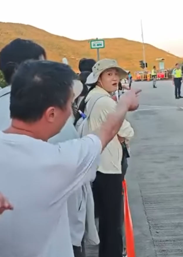 西貢萬宜水庫東壩多名排隊等候人士鼓噪不滿有旅客沒排隊就登上小巴,其後獲警員告知是「包車」。(影片截圖)