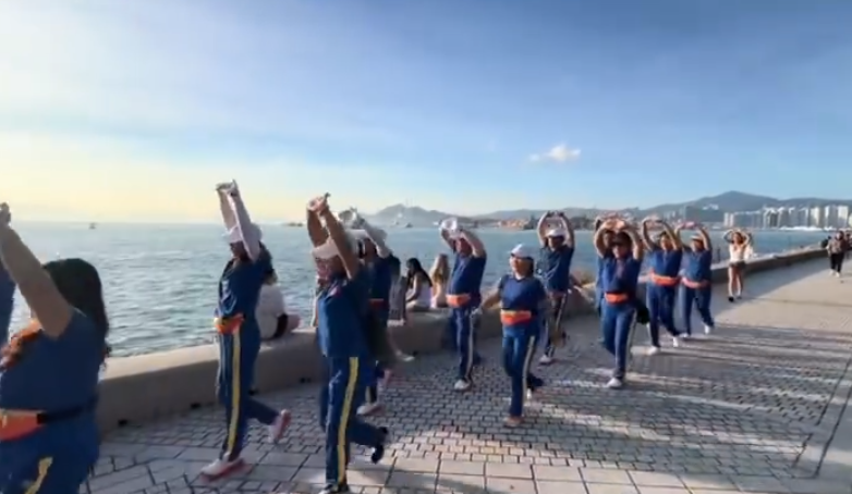 內地屢引發爭議的「暴走團」殺入香港,現身西九文化區徒步和做伸展運動,沿途大聲播放音樂影片,惹來旁邊市民及遊客側目。(影片截圖)