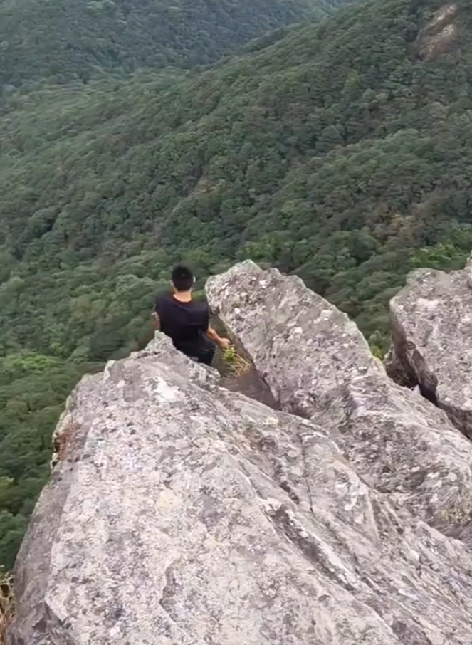 有「東莞第一高峰」之稱、海拔高達898米的銀瓶山,一名男子在懸崖邊緣打座「練功」。(影片截圖)