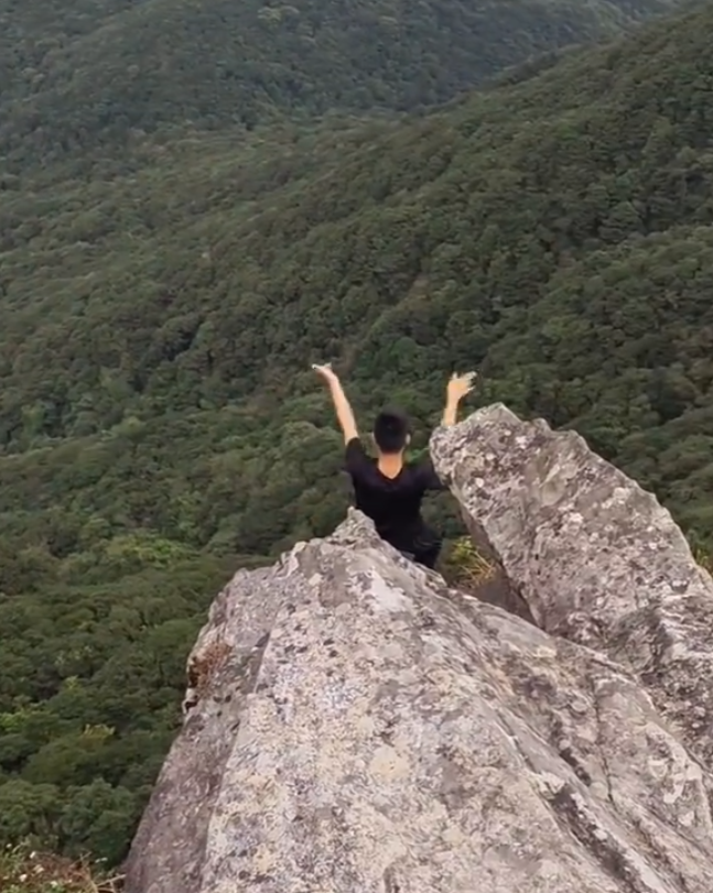 有「東莞第一高峰」之稱、海拔高達898米的銀瓶山,一名男子在懸崖邊緣打座「練功」。(影片截圖)