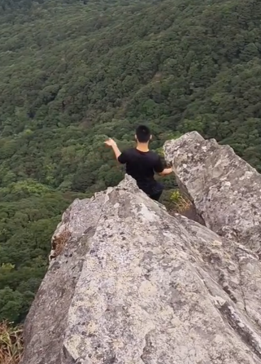 有「東莞第一高峰」之稱、海拔高達898米的銀瓶山,一名男子在懸崖邊緣打座「練功」。(影片截圖)