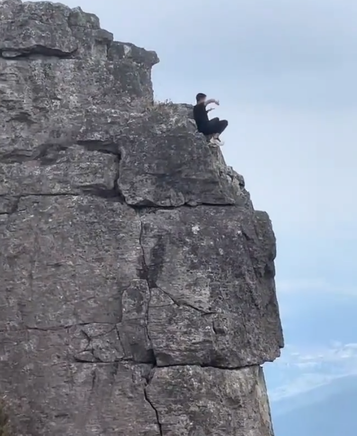 有「東莞第一高峰」之稱、海拔高達898米的銀瓶山,一名男子在懸崖邊緣打座「練功」。(影片截圖)