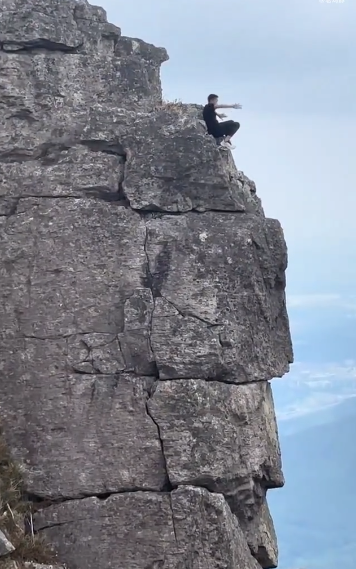 有「東莞第一高峰」之稱、海拔高達898米的銀瓶山,一名男子在懸崖邊緣打座「練功」。(影片截圖)