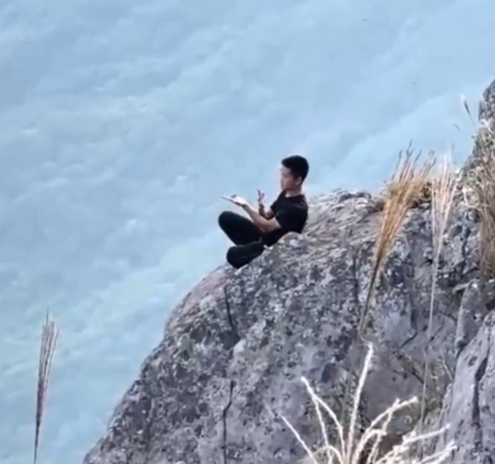 有「東莞第一高峰」之稱、海拔高達898米的銀瓶山,一名男子在懸崖邊緣打座「練功」。(影片截圖)