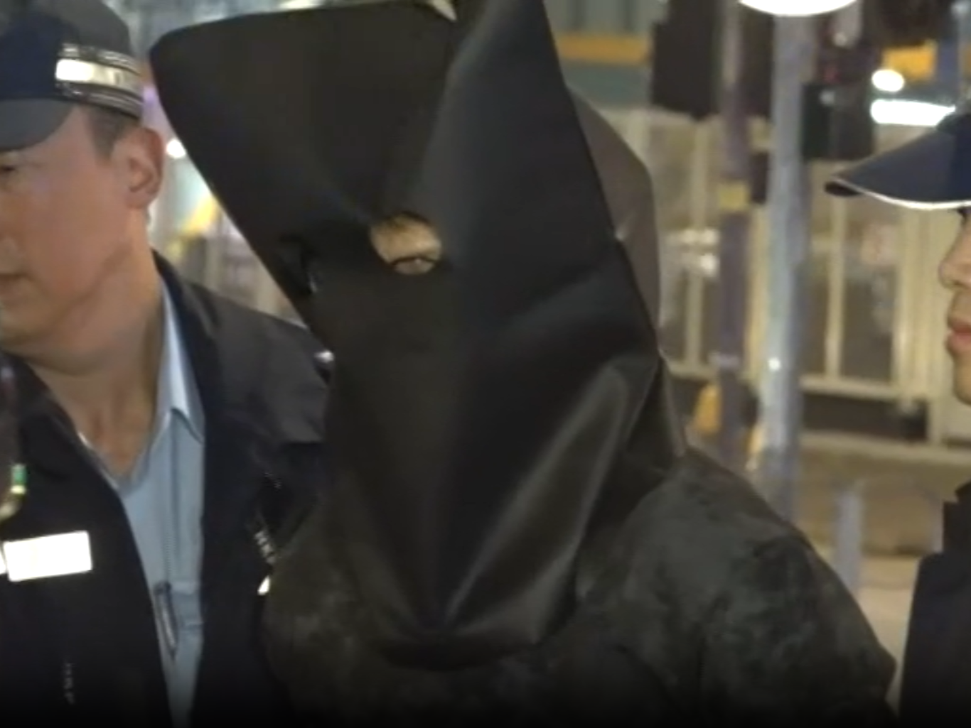 被捕男子黑布蒙頭鎖上手銬,押到涉事私家車旁邊調查。(now新聞截圖)