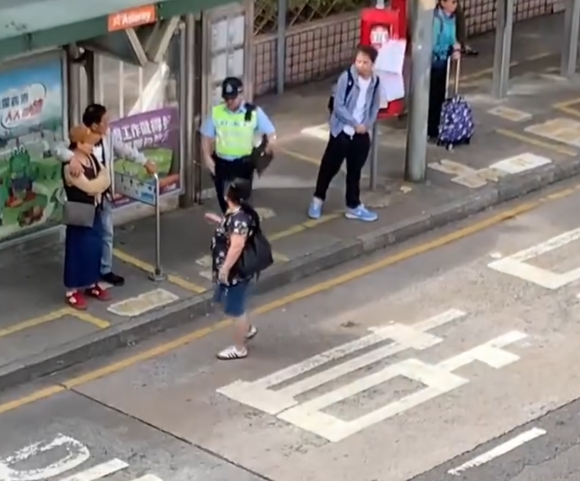 上水一名婦人「打斜」橫過馬路,走到對面巴士站時遭守候警員「斷正」,但婦人看到警員後「揮了一下手」未有停下,警員逐跟在身後走了幾步,最終成功截停對方。(Threads影片截圖)