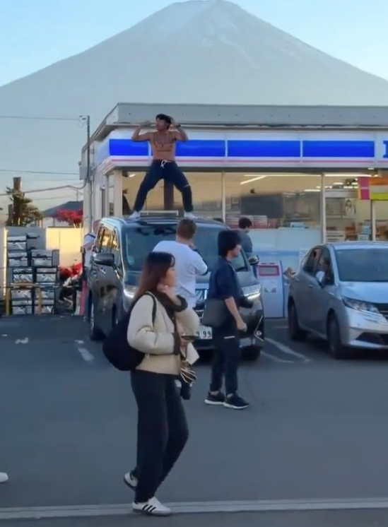 日本山梨縣富士河口湖町的LAWSON便利店外,泰國網紅Jack Papho在店前一輛車的車頂上半裸跳舞。(影片截圖)