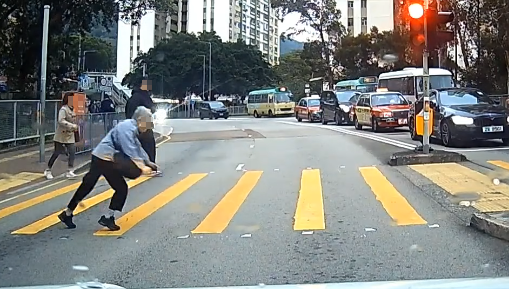 一名婆婆過馬路疑因綠燈正在「閃燈」,情急下失平衡在路中心向前仆倒,連鞋也甩脫,附近一對男女見狀即上前協助扶起 (facebook群組「車cam L(香港群組)」)