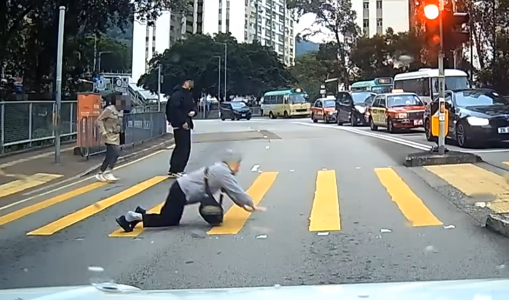 一名婆婆過馬路疑因綠燈正在「閃燈」,情急下失平衡在路中心向前仆倒,連鞋也甩脫,附近一對男女見狀即上前協助扶起 (facebook群組「車cam L(香港群組)」)