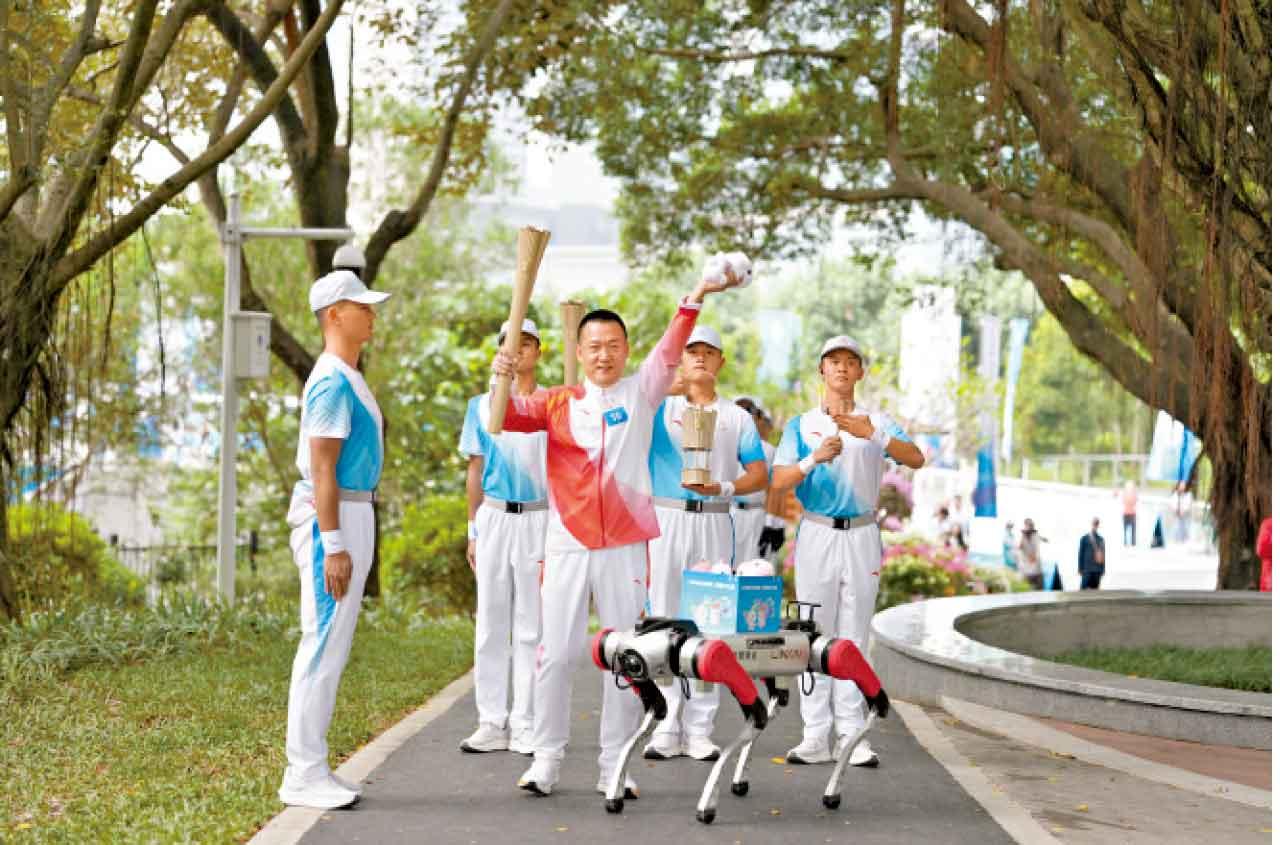 機器狗將十五運會吉祥物玩偶交予火炬手。(新華社)