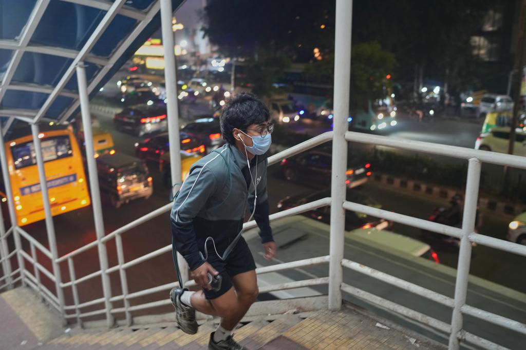 11月18日早上,印度新德里有人戴口罩跑上樓梯。(美聯社)