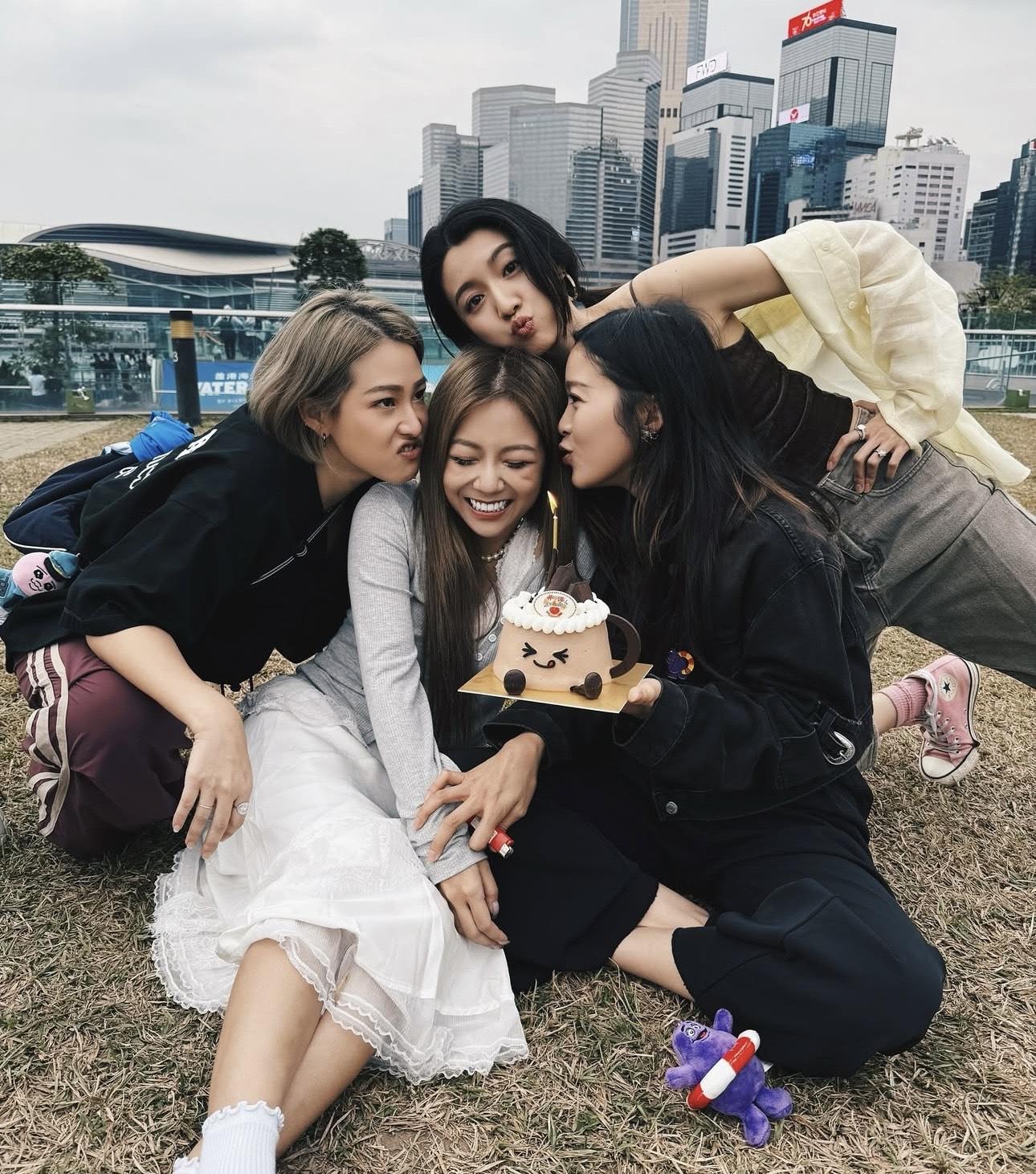 四人坐在草地上慶祝,非常青春。