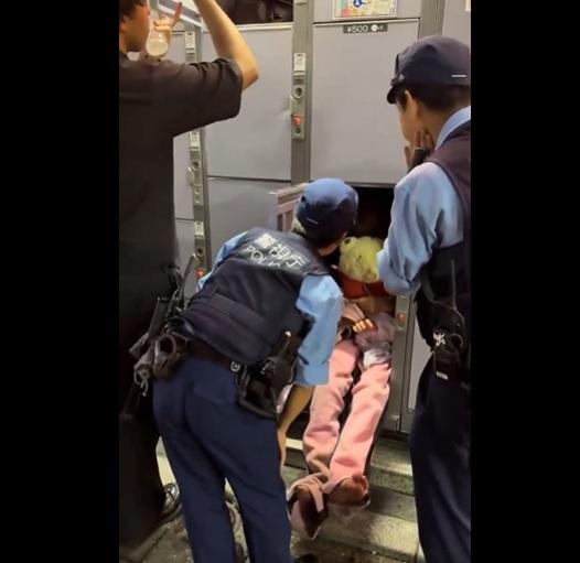年輕女子抱著小熊維尼公仔睡在儲物櫃裡,警員把她喚醒。(互聯網)