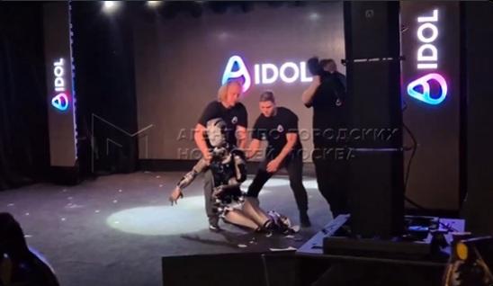 AIdol突然跌倒,工作人員將它扶起,另一人在後方拉起黑布。(互聯網)