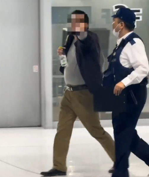 警察登機將男子帶走時仍在機場與乘客爭執。(影片截圖)