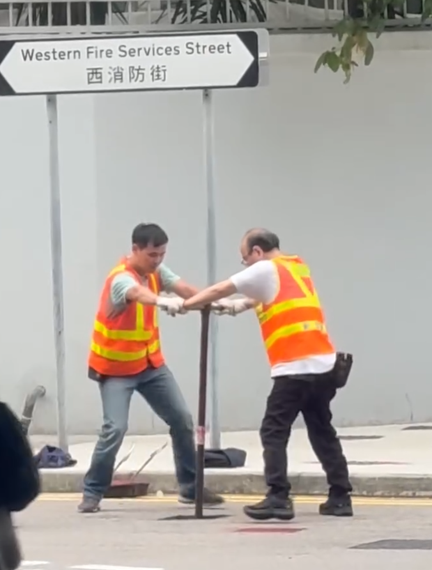 上環西消防街兩名工人在馬路進行維修工作開關水掣,他們面對面、雙手交疊合力轉動閥門的動作極具默契,遠看彷彿是一對正在跳華爾茲舞的拍擋。另外,影片可見附近恰巧有三隻狗路過,成為網民「錯重點」討論對象。(Threads)