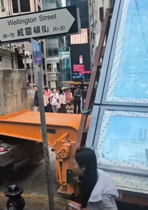一輛載有玻璃窗等大型建築材料的大型貨車,撞到「威靈頓街」路牌。路牌被撞後傾斜近45度角,最後貨車離開現場,事後引來不少市民及遊客圍觀擺甫士「打卡」拍照。(SH Hong@車cam L(香港群組)FB)
