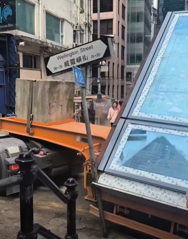 一輛載有玻璃窗等大型建築材料的大型貨車,撞到「威靈頓街」路牌。路牌被撞後傾斜近45度角,最後貨車離開現場,事後引來不少市民及遊客圍觀擺甫士「打卡」拍照。(SH Hong@車cam L(香港群組)FB)