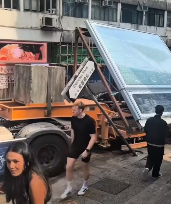 一輛載有玻璃窗等大型建築材料的大型貨車,撞到「威靈頓街」路牌。路牌被撞後傾斜近45度角,最後貨車離開現場,事後引來不少市民及遊客圍觀擺甫士「打卡」拍照。(SH Hong@車cam L(香港群組)FB)