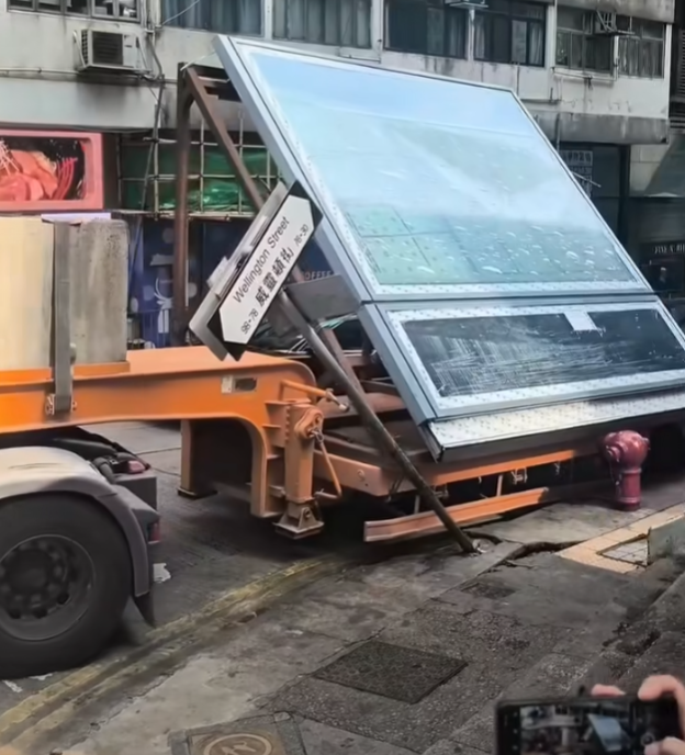 一輛載有玻璃窗等大型建築材料的大型貨車,撞到「威靈頓街」路牌。路牌被撞後傾斜近45度角,最後貨車離開現場,事後引來不少市民及遊客圍觀擺甫士「打卡」拍照。(SH Hong@車cam L(香港群組)FB)