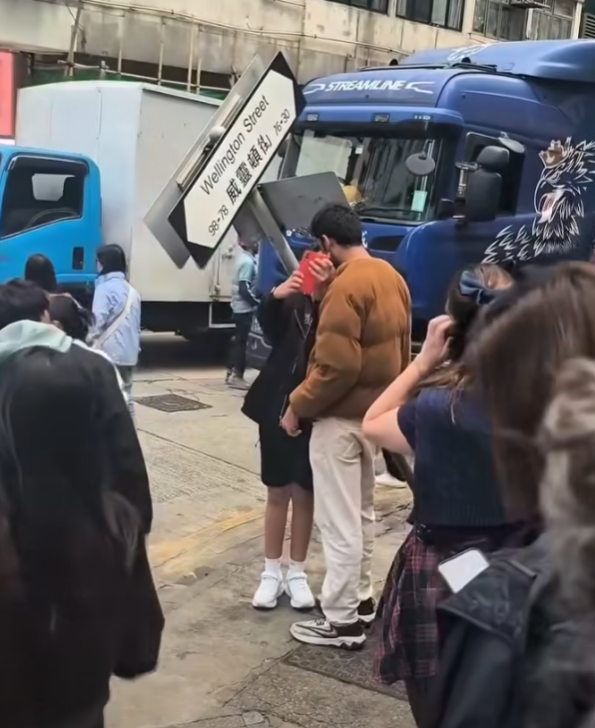 一輛載有玻璃窗等大型建築材料的大型貨車,撞到「威靈頓街」路牌。路牌被撞後傾斜近45度角,最後貨車離開現場,事後引來不少市民及遊客圍觀擺甫士「打卡」拍照。(SH Hong@車cam L(香港群組)FB)