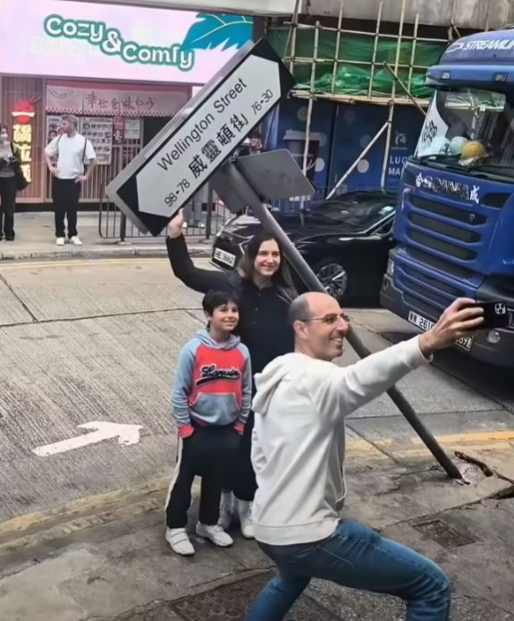 一輛載有玻璃窗等大型建築材料的大型貨車,撞到「威靈頓街」路牌。路牌被撞後傾斜近45度角,最後貨車離開現場,事後引來不少市民及遊客圍觀擺甫士「打卡」拍照。(SH Hong@車cam L(香港群組)FB)