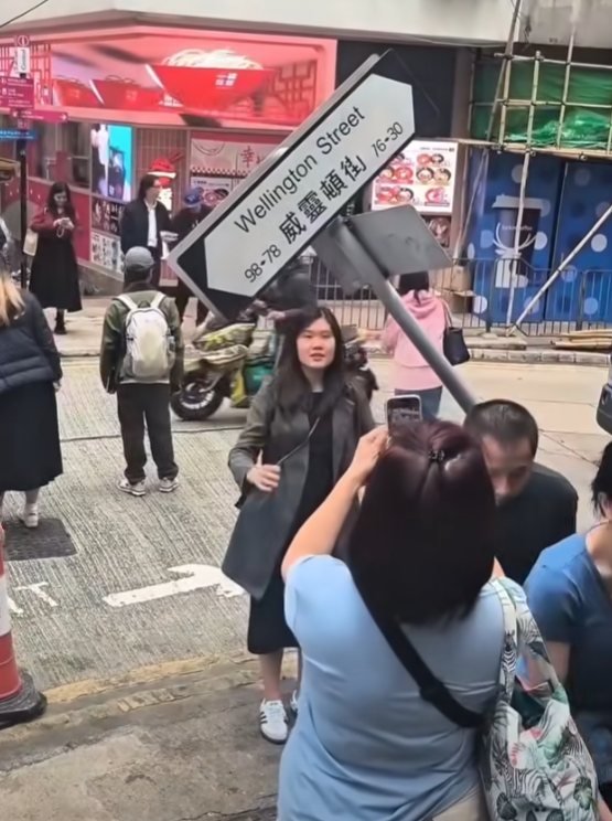 一輛載有玻璃窗等大型建築材料的大型貨車,撞到「威靈頓街」路牌。路牌被撞後傾斜近45度角,最後貨車離開現場,事後引來不少市民及遊客圍觀擺甫士「打卡」拍照。(SH Hong@車cam L(香港群組)FB)