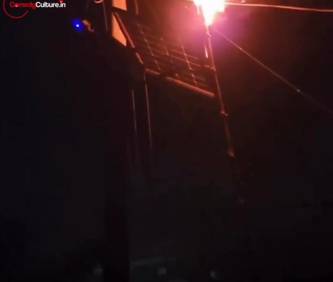 男子手持一根一端正在燃燒的木棍,並將火焰朝向太陽能板照射。(IG)