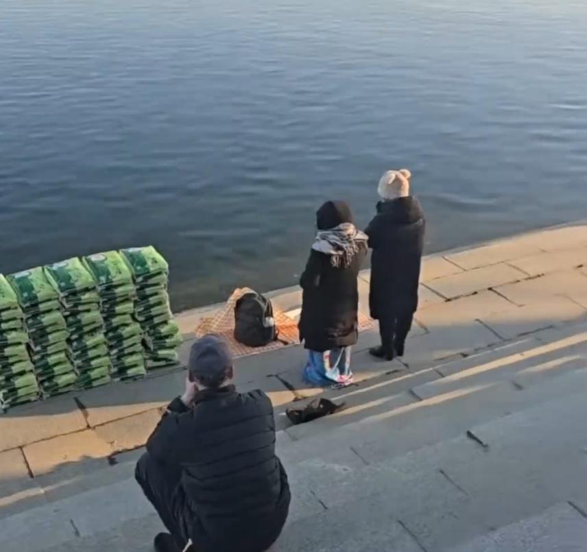 有民眾帶著多袋白米到江邊,在現場跪拜後,把白米倒入江裡。(微博)