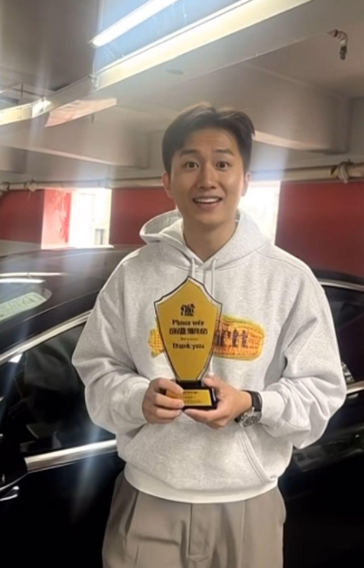 GM手持獎杯笑容滿面地望向鏡頭。