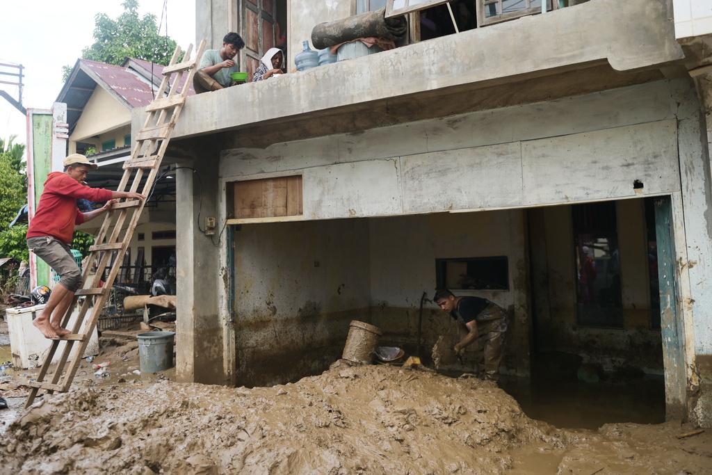 印尼水災後,亞齊省有災民清理屋內的泥濘。(美聯社)