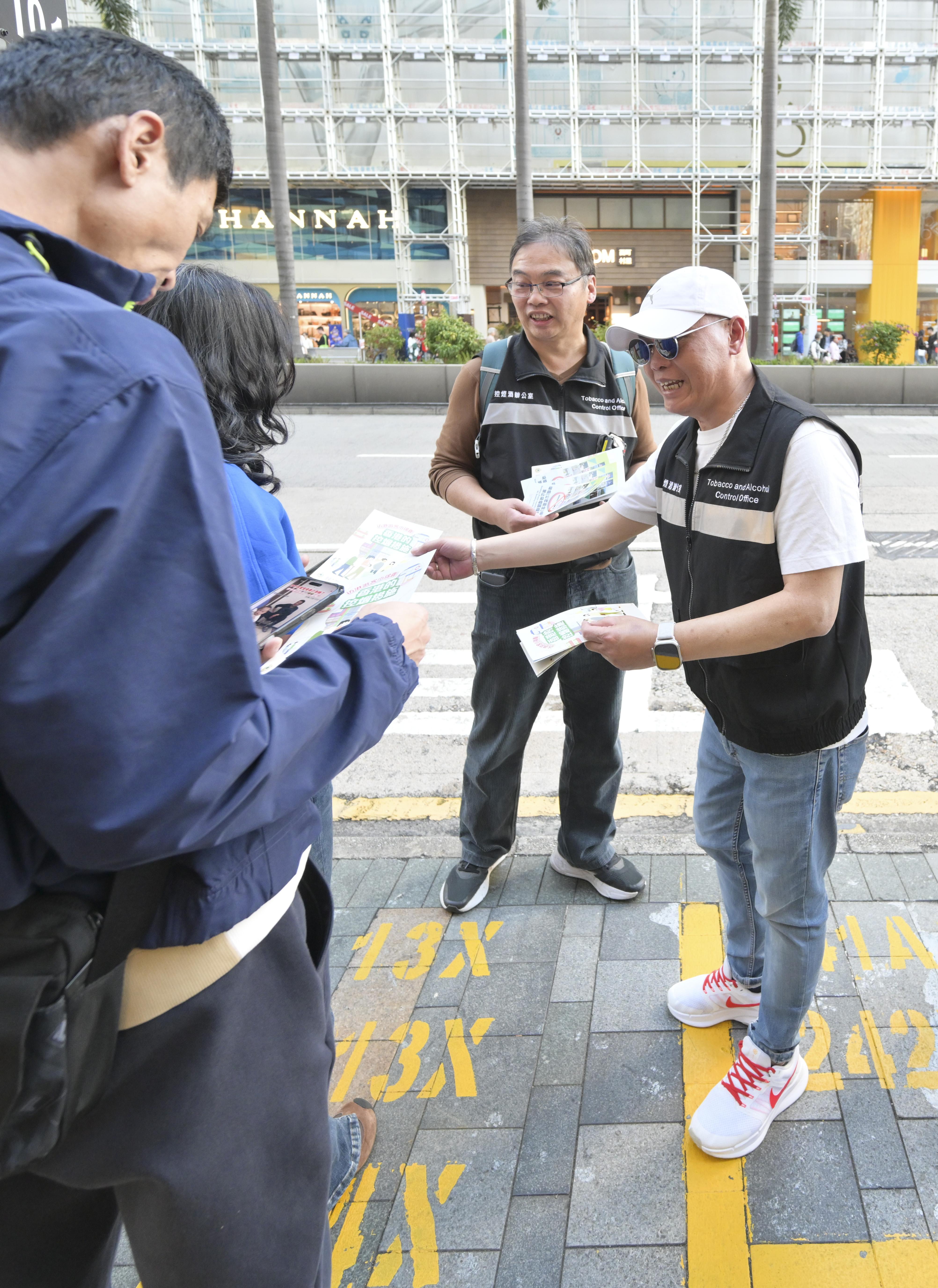 圖示控煙酒辦人員於尖沙咀一巴士站向市民派發有關控煙措施的宣傳單張。(政府新聞處)