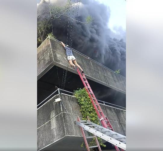 女子緊抓圍欄扶手,把腳探向2樓位置。(互聯網)