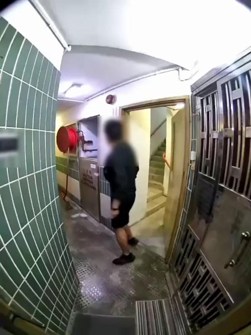 網傳宏福苑大火期間宏建閣的閉路電視片段,一名男居民經防火梯進入一樓層,嘗試敲打火警鐘惟警鐘未有響起。(網上片段截圖)