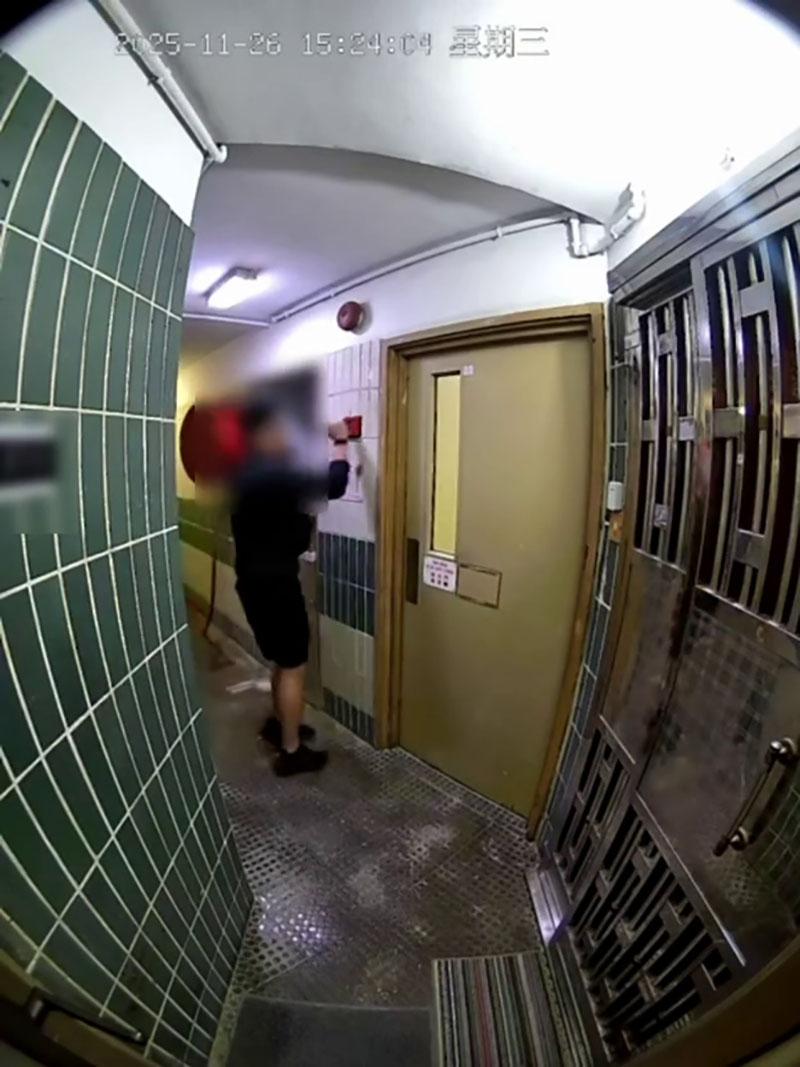 網傳宏福苑大火期間宏建閣的閉路電視片段,一名男居民經防火梯進入一樓層,嘗試敲打火警鐘惟警鐘未有響起。(網上片段截圖)