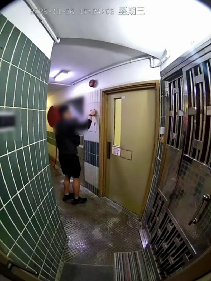 網傳宏福苑大火期間宏建閣的閉路電視片段,一名男居民經防火梯進入一樓層,嘗試敲打火警鐘惟警鐘未有響起。(網上片段截圖)