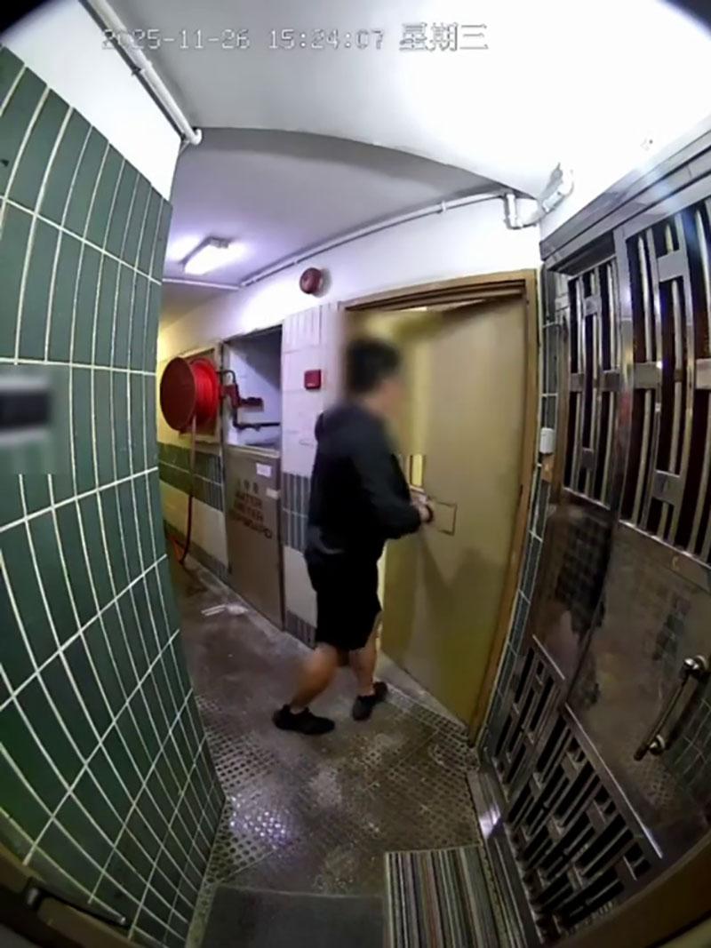 網傳宏福苑大火期間宏建閣的閉路電視片段,一名男居民經防火梯進入一樓層,嘗試敲打火警鐘惟警鐘未有響起。(網上片段截圖)