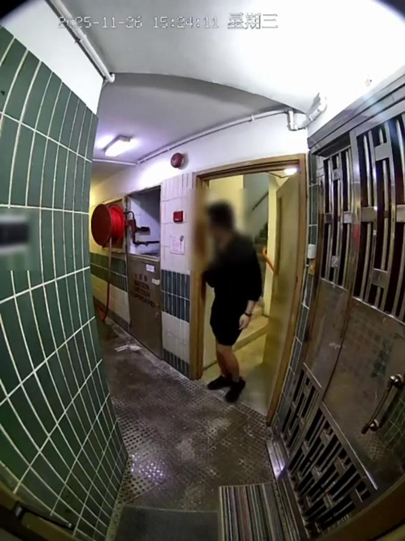 網傳宏福苑大火期間宏建閣的閉路電視片段,一名男居民在一樓層敲打火警鐘不果後準備離去,期間有女鄰居上前稱「嗰度燒得好緊要」。(網上片段截圖)