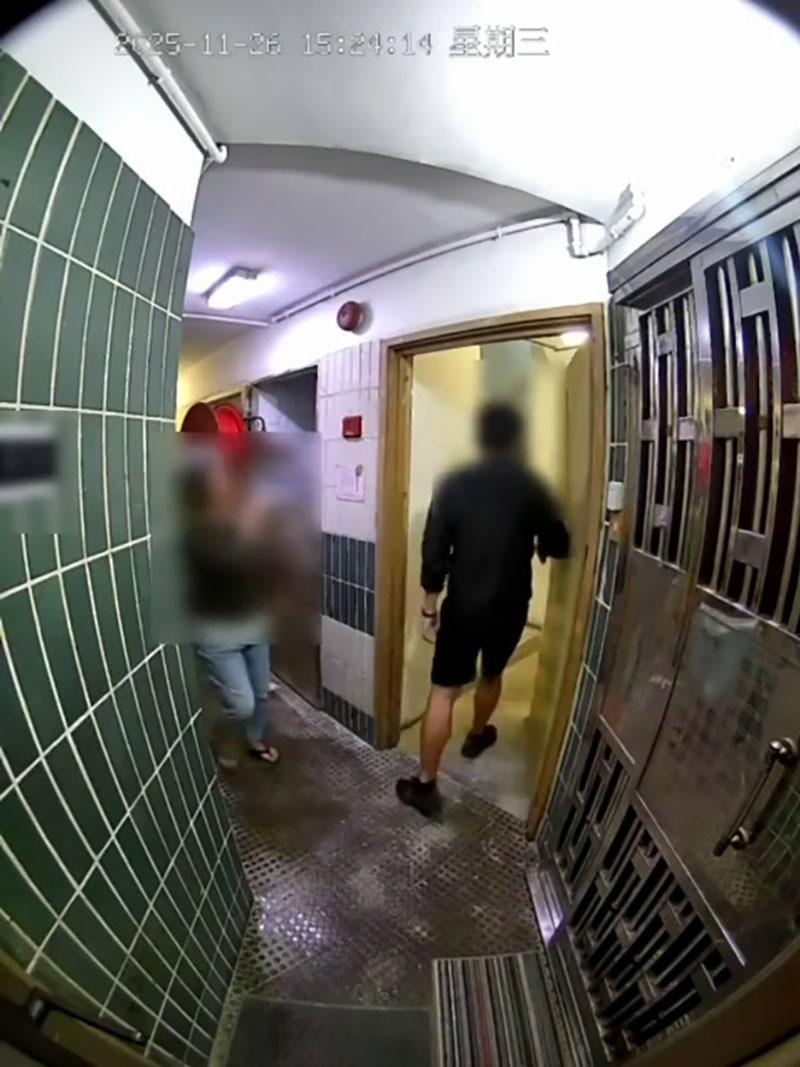 網傳宏福苑大火期間宏建閣的閉路電視片段,一名男居民在一樓層敲打火警鐘不果後準備離去,期間有女鄰居上前稱「嗰度燒得好緊要」。(網上片段截圖)