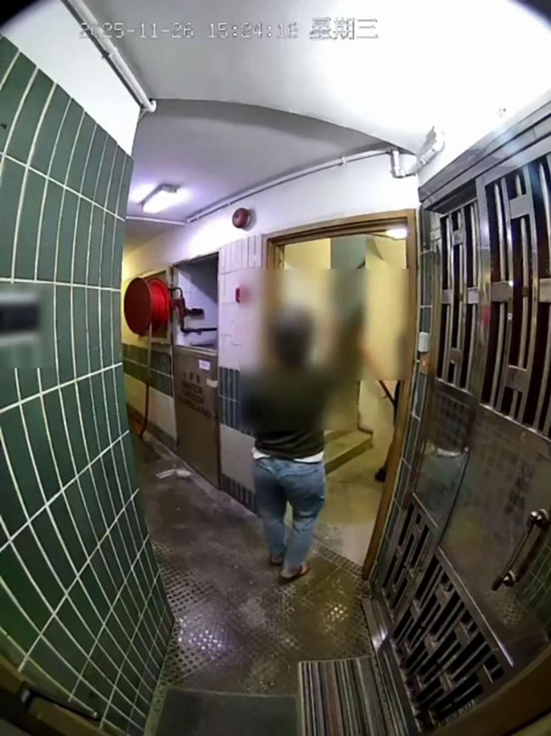 網傳宏福苑大火期間宏建閣的閉路電視片段,一名男居民在一樓層敲打火警鐘不果後準備離去,期間有女鄰居上前稱「嗰度燒得好緊要」。(網上片段截圖)